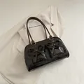 Dark brown patent leather shoulder bag with chic bow details on a white blazer - Coffee No Charm