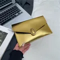 Pochette a busta dorata con trama Saffiano ed elegante fibbia metallica ad anello - Oro