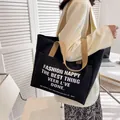 Schwarze Canvas-Tragetasche mit beige Griffen und weißem Buchstabenaufdruck für Alltag - Schwarz