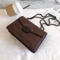 Borsa a tracolla trapuntata marrone scuro con borchie e catena in un set fotografico - Marrone