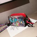 Red camera bag with graffiti art, dual zippers, and colorful woven wide strap - Red