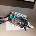 Light blue graffiti camera bag with artistic prints and wide geometric shoulder strap - Blue