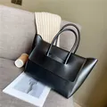 Minimalistische schwarze matte Leder-Einkaufstasche mit integriertem Griff auf Sofa - Schwarz