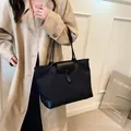 Minimalist black oxford fabric tote bag with leather straps worn on shoulder by model - Black
