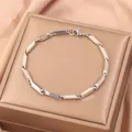 Gros plan d'un bracelet gourmette en acier poli avec fermoir mousqueton sur soie - Argent