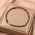 Détail d'un bracelet à maillons noirs avec fermoir mousqueton dans son écrin cadeau - Noir