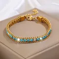 Gros plan d'un bracelet en acier titane doré orné de strass bleus et blancs - Bracelet Or Bleu Clair Zircone Blanche