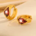 Détail de boucles d'oreilles en acier doré avec zircons rouges en forme de poire - Boucles d'oreilles goutte d'eau / Bordeaux