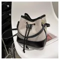 Bolso tipo cubo de lona y cuero con cordón ajustable en una silla moderna - Negro
