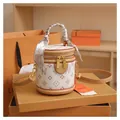 Dettaglio di una borsa a secchiello bianca e marrone monogramma su scatola arancione - Bianco