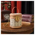 Creamy white bucket bag with brown bear pattern and orange top handle on wooden table - Off White