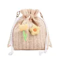 Stroh-Eimertasche mit Perlenkette und gelben Blumen-Patches auf weißem Hintergrund - Beige