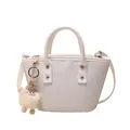 White woven bucket bag with dual handles and plush charm detail for summer style - White