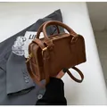 Detail of a brown leather Boston bag showing the top zipper and sturdy handle grip - Brown
