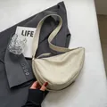 Minimalist beige dumpling shoulder bag with textured finish and wide strap on grey suit - Off White