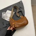 Brown vintage faux leather crossbody bag with geometric pattern wide strap on a desk - Brown