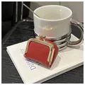 Macro detail of red lychee grain leather mini purse with gold kiss-lock closure - Red