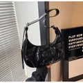 Black crescent shoulder bag featuring glossy faux leather and stylish criss-cross lacing - Black