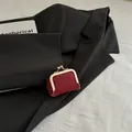 Mini red lychee leather coin purse with golden kiss-lock on a black blazer - Red