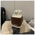 Gros plan du sac seau tissé avec poignée en perles et bandoulière en chaîne dorée - Café