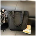 Minimalistische zwarte canvas shopper met stevige handvatten op een leren bankstel - Zwart