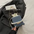 Dunkelblaue gewebte Beuteltasche mit Perlengriff und goldener Kette auf schwarzem Sakko - Blau