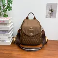 Brown nylon quilted backpack with striped strap shown on a wooden desk with plants - Brown