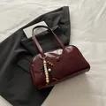 Deep red leather shoulder bag with decorative wooden bead tassel and outer pocket detail - With Pendant / Red