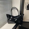 Glossy black leather tote bag with gold buckle on a windowsill for daily commute - Black