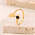 Gros plan détaillé d'une bague feuille dorée avec perle noire sur pierre brute - Feuille d'Or Avec Émail Noir