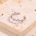Gros plan d'une bague argentée ondulée sertie de micro-oxydes de zirconium brillants - Ouvert / Argent Strass Blanc
