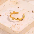 Détail d'une bague ondulée en acier titane doré avec pierres colorées sur socle en pierre - Ouvert / Or avec zircon multicolore
