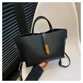 Minimalist black lychee leather tote bag with gold oval twist lock and slim shoulder strap - Black