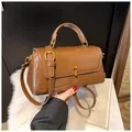 Macro detail of brown patent leather handbag with golden twist lock on plush white background - Brown