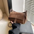 Bolso bandolera marrón con textura granulada, costuras blancas y colgante suave - Café