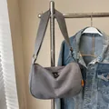 Minimalist grey corduroy dumpling crossbody bag with adjustable wide strap and orange label - Gray