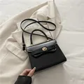 Elegante bolso de mano en cuero sintético negro brillante con cierre de metal dorado - Negro