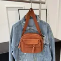Stylish brown corduroy crossbody bag with woven strap shown over a denim jacket - Brown
