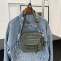 Green corduroy crossbody bag with front pocket and dual woven zipper pulls on denim jacket - Green