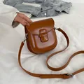 Borsa a tracolla a mezzaluna marrone caramello con fibbia argento su un letto bianco - Marrone
