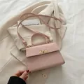 Sac bandoulière rose mat avec boucle dorée posé sur un blazer crème élégant - Rose