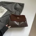 Dunkelbraune Hobo-Tasche aus Leder und Wildleder mit Goldkette auf grauem Sakko - Braun