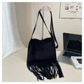 Detailed view of black suede shoulder bag featuring long fringe tassels and a slim strap - Black