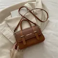 Caramel brown box-shaped crossbody bag with silver hardware and top handle on beige background - Brown