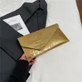 Chic gold envelope clutch bag with crocodile texture on a professional gray suit - Gold