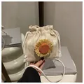Close-up of beige woven bucket bag with sunflower detail and white cotton strap - Khaki with Orange Sunflower