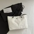 White marble texture tote bag with black handles and silver logo on a flat lay - White Without Pendant