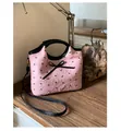 Détail du sac matelassé rose avec imprimés nœuds et ruban noir sur une table en bois - Grand nœud rose (Style 1)