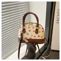 Dettaglio della stampa a ciliegia su borsa in pelle beige con doppia cerniera dorata - Marrone