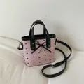 Detail einer rosa Bucket Bag mit schwarzem Schleifenmuster und Herz-Metallanhänger - Quadratischer Eimer Stil (Modell 2)